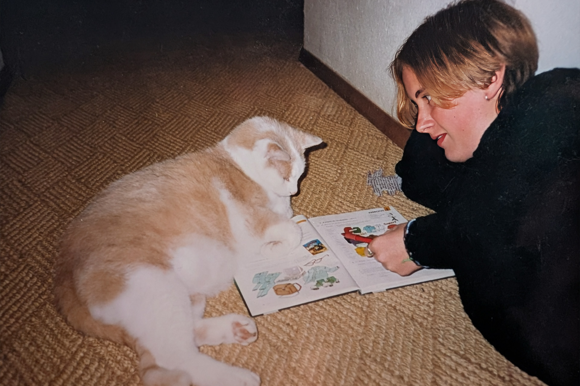 Melly liegt mit Katze Mikesch auf dem Boden und liest ein Buch – Kindheitserinnerung aus dem Schwarzwald